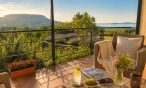 Fedett terasz fonott fotelekkel, háttérben a Badacsony és a Balaton